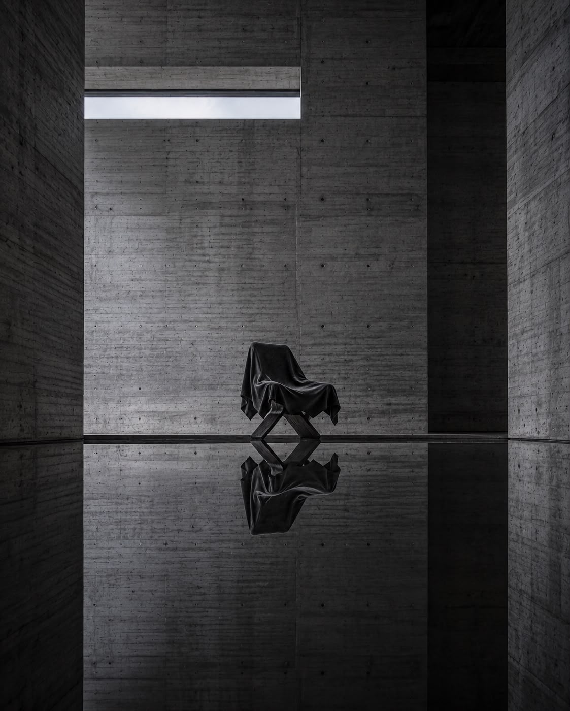 DRAPE veiled sculptural chair in a tall concrete room with dark reflection